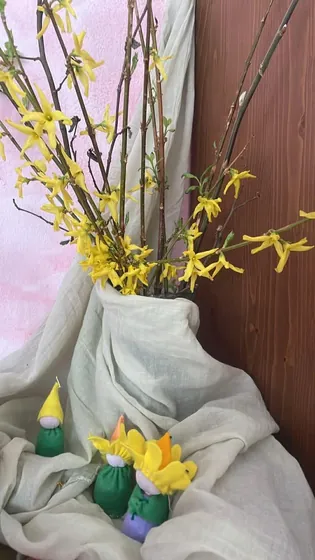 Gałązki forsycji w chuście, obok filcowe krasnale i żonkile