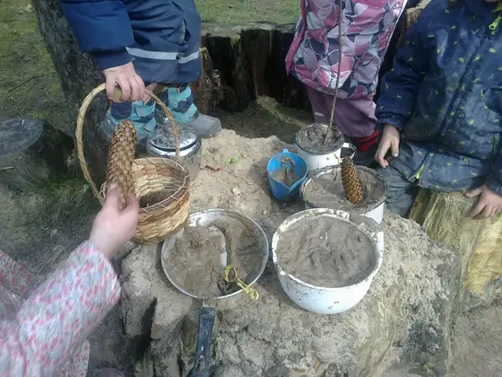 Metalowe miski z ziemią i piaskiem na kamiennym blacie kuchni błotnej