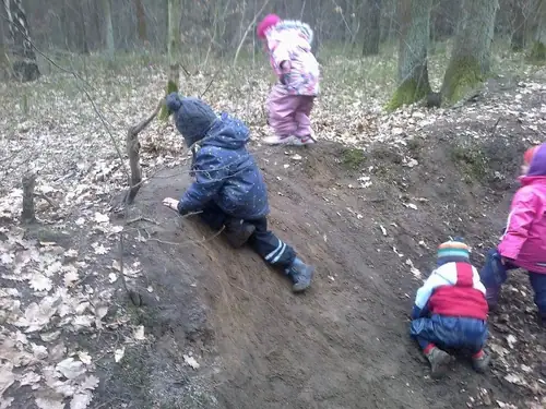 Dzieci wspinają się na piaszczystą skarpę w lesie