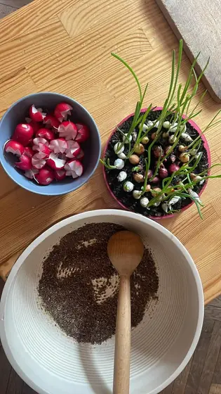 Miski z rzodkiewkami, zieleniną i kaszą z drewnianą łyżką