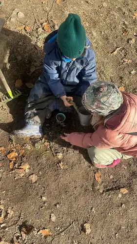 Dwoje dzieci w czapkach kopie w ziemi, widok z góry