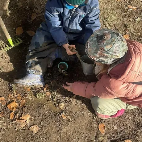 Dwoje dzieci w czapkach kopie w ziemi, widok z góry